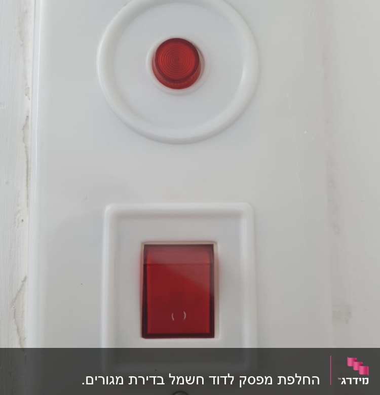 מתג חשמלי עם כפתור אדום על קיר לבן
